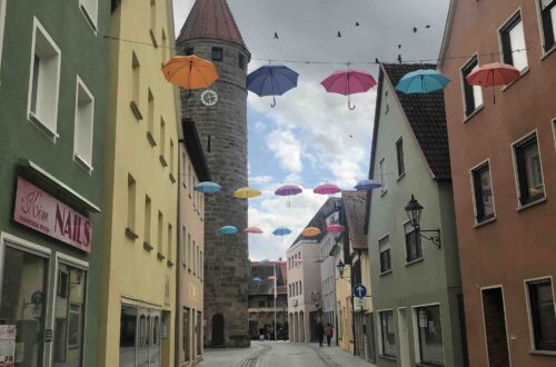 Marktstraße in Gunzenhausen mit Blick auf den Turm. Die Straße ist mit bunten Regenschirmen geschmückt.