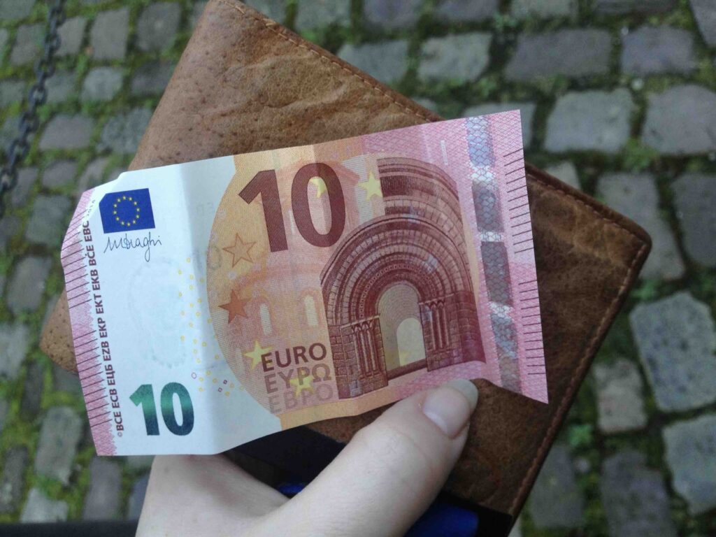 Hand die ein Portmonee mit einem 10 Euro Schein hält. 