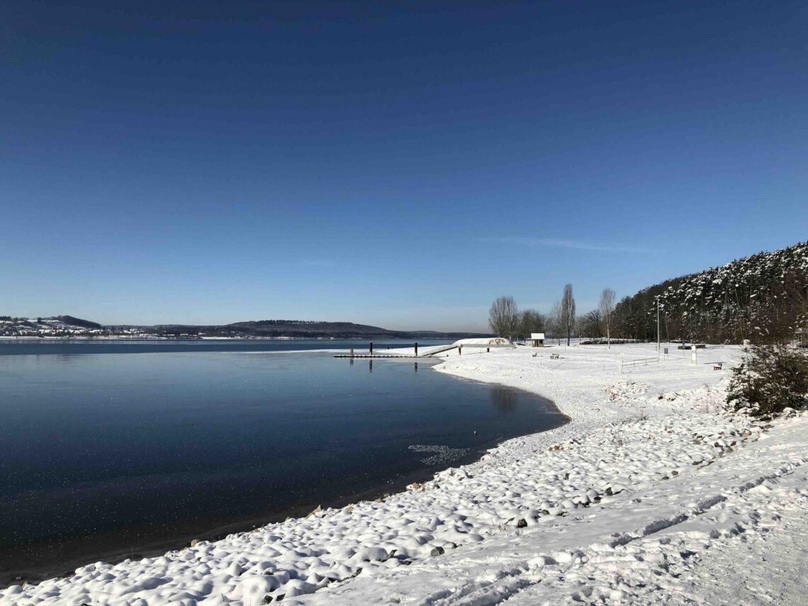 Brombachsee verschneit und leicht zugefroren mit blauen Himmel