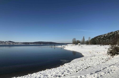 Brombachsee verschneit und leicht zugefroren mit blauen Himmel