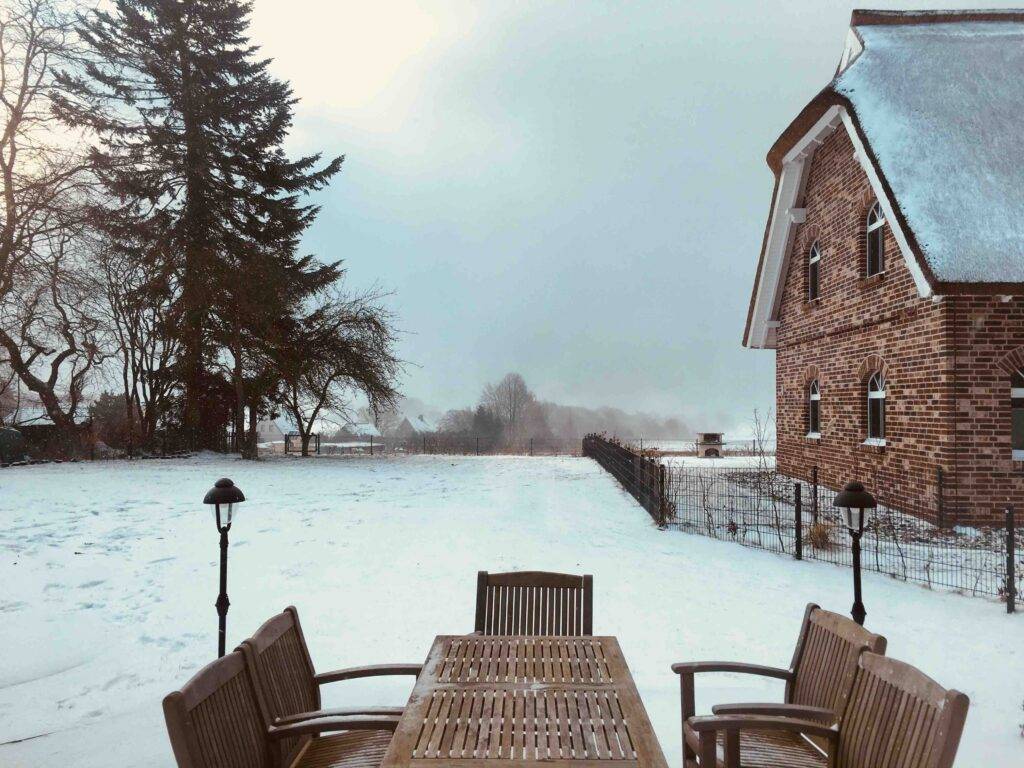 Wokation in Putbus: Blick von einem Ferienhaus auf das andere. Dazwischen eine Terrasse mit Sitzgruppe.