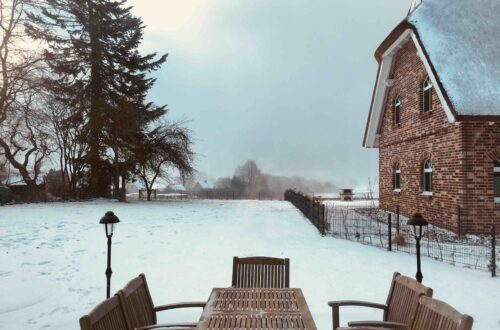 Wokation in Putbus: Blick von einem Ferienhaus auf das andere. Dazwischen eine Terrasse mit Sitzgruppe.