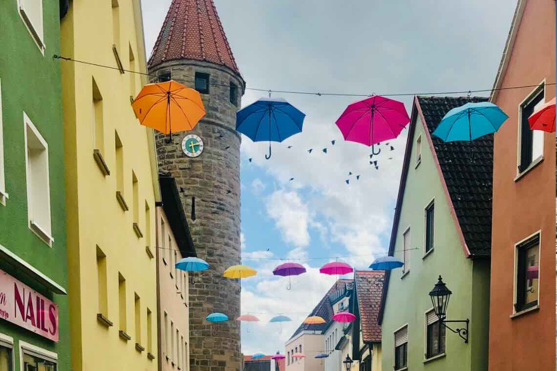 Marktstraße in Gunzenhausen mit Blick auf den Turm. Die Straße ist mit bunten Regenschirmen geschmückt.