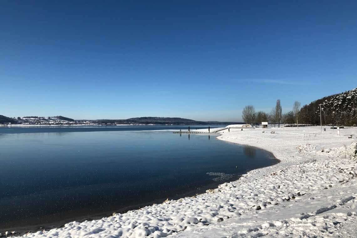 Brombachsee verschneit und leicht zugefroren mit blauen Himmel
