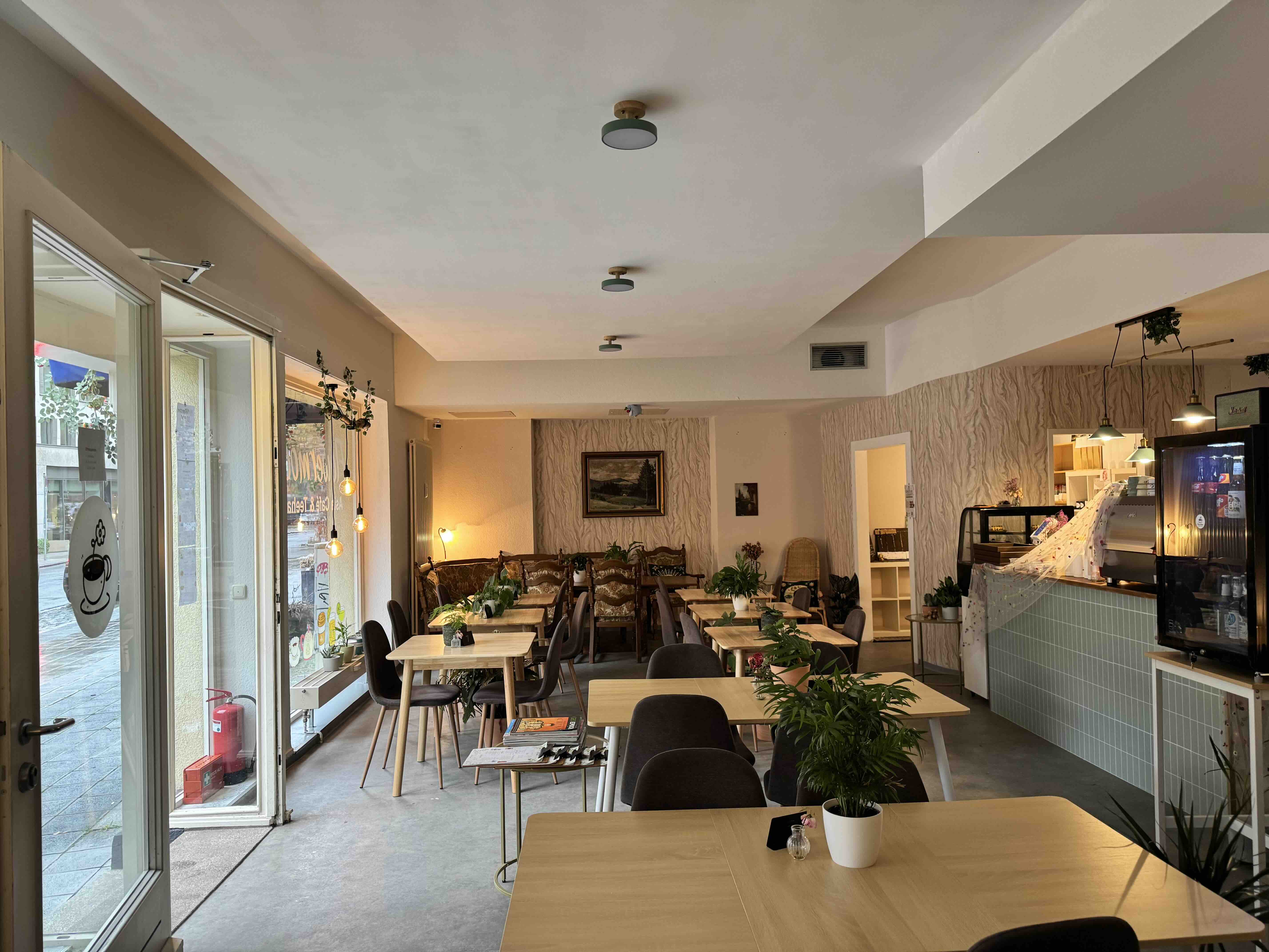 Innenraum des Café Flowermoon Nürnberg mit Holztischen und Pflanzen